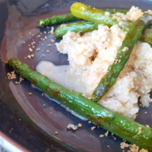 Cinq asperges et une portion de quinoa dans une assiette noire