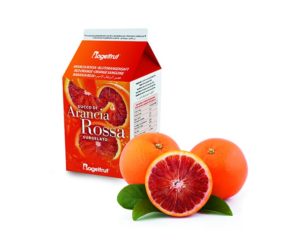 Une brique de Jus d’Orange Sanguine Surgelé à côté de deux oranges sanguines entières et une demi orange sanguine sur fond blanc