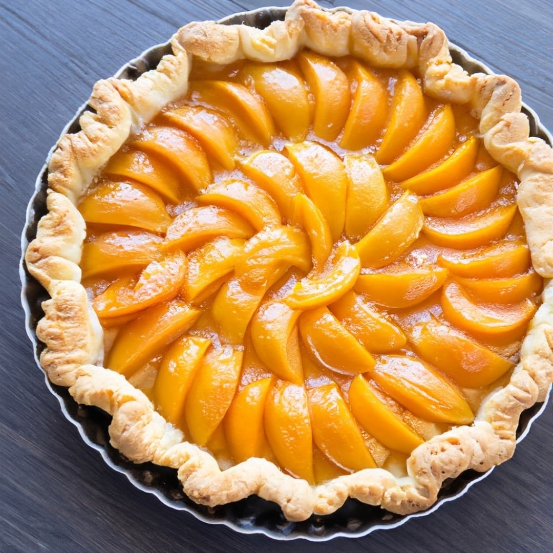 une tarte mirabelle et abricot dans un plat en fer et vu de haut sur une table en bois